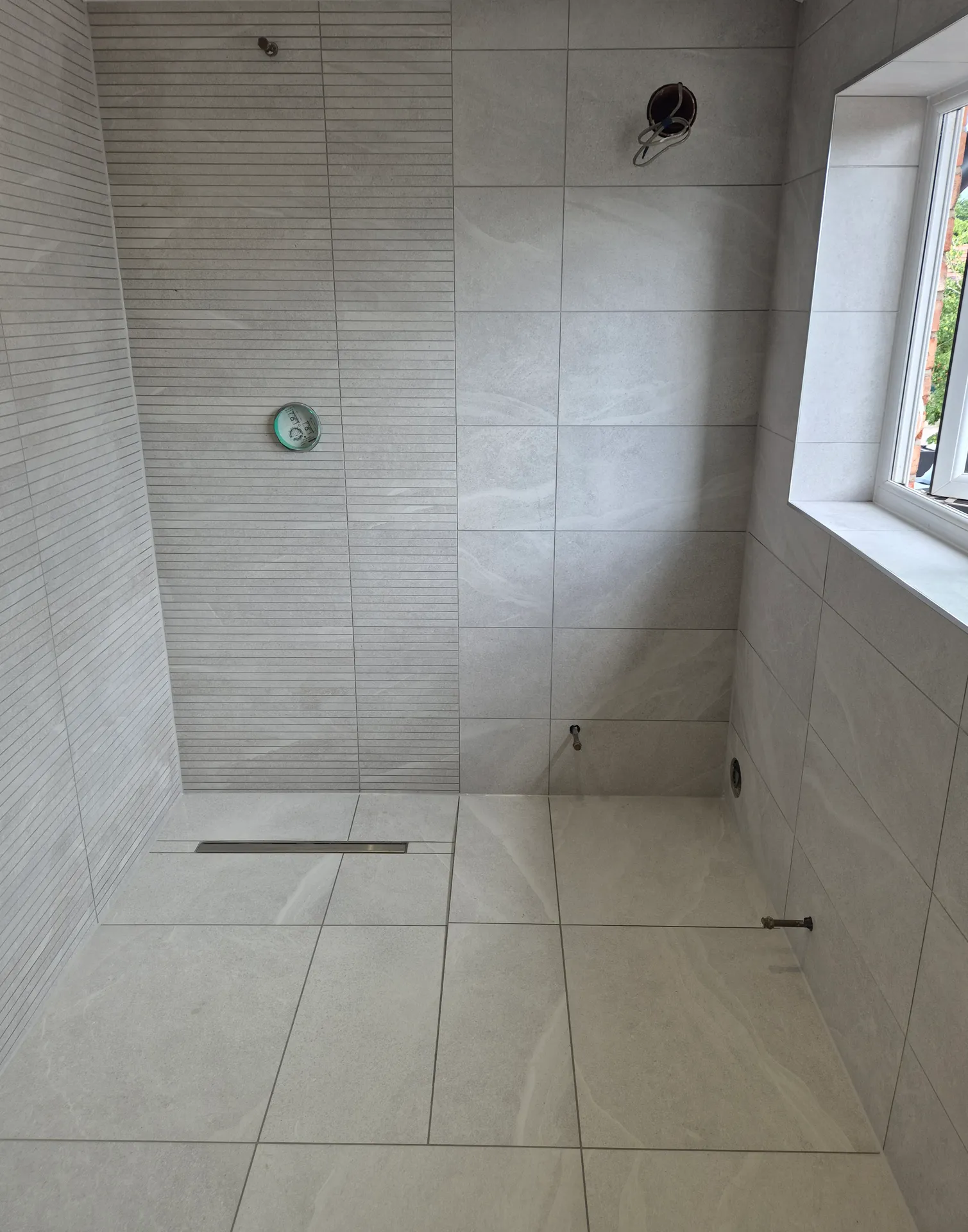 Finished stone-effect wet room in Warrington — large-format porcelain walls and floor with a linear drain and feature tile band