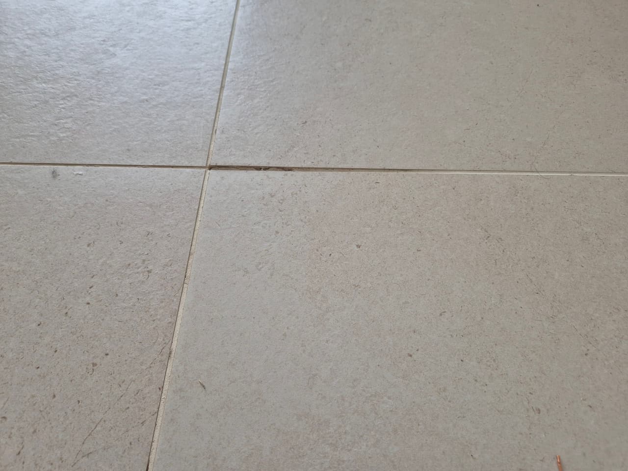 Existing tiled ground floor before removal, close-up of the worn ceramic surface