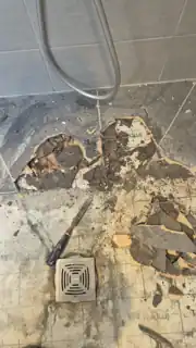 Wet room former during initial investigation showing large isolated adhesive pads beneath removed tiles